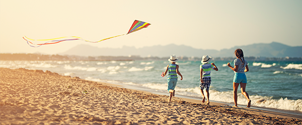 Kids chasing kite on beach