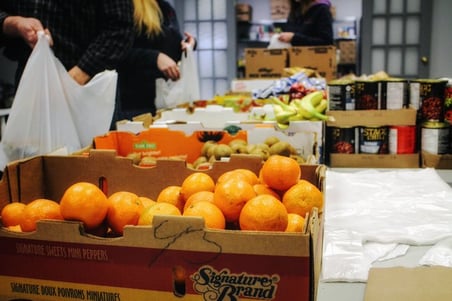 Volunteers packaging food for children. Each package has a selection of fresh fruit and vegetables. 