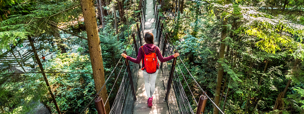 Woman hiking across a suspension bridge