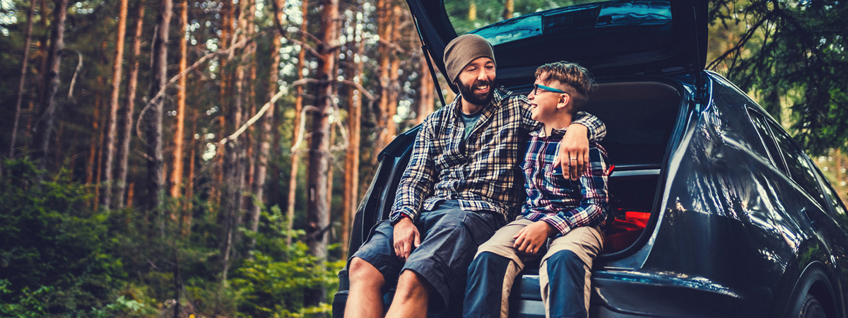 Father and son travelling by car in the forest.