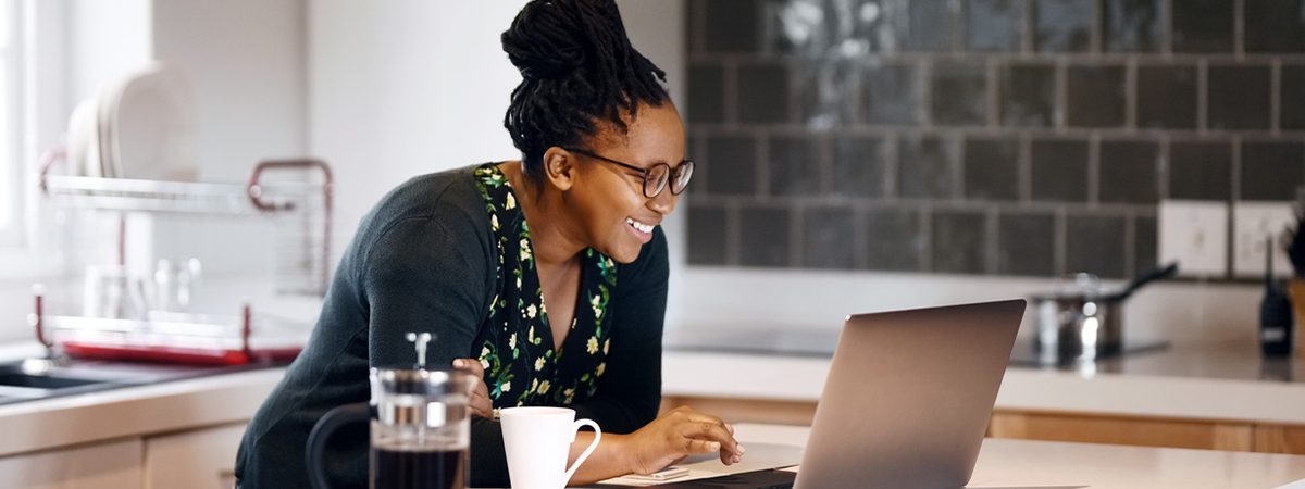 Young women working on computer in kitchen.