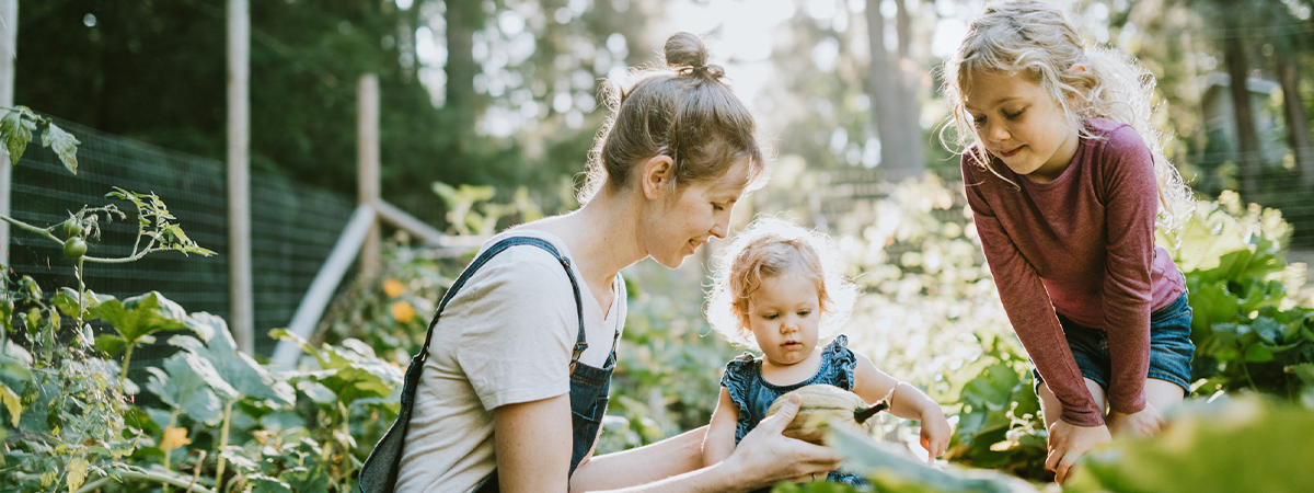 Mother showing daughters food from vegetable garden