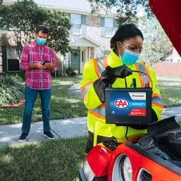 Female CAA technician installing CAA battery into man's car.