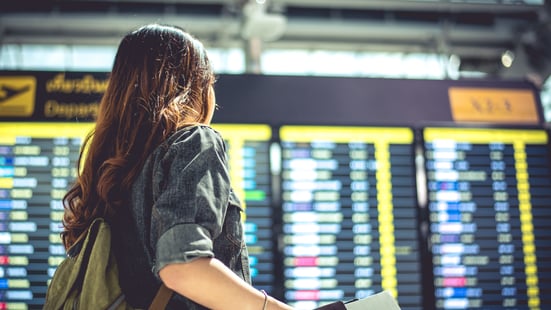 female tourist looking at flight schedules for checking take off time.