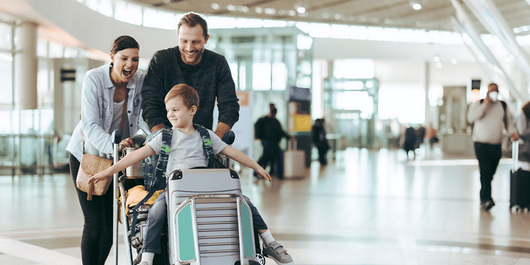 woman and man push child on luggage in airport