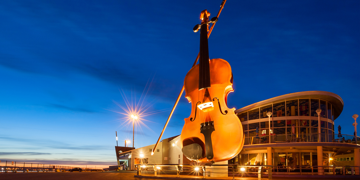 "Sydney, Canada - June 13, 2009: The Visitor Centre and Cruise Ship Terminal illuminated in the evening with the world's largest fiddle in Sydney, Nova Scotia."