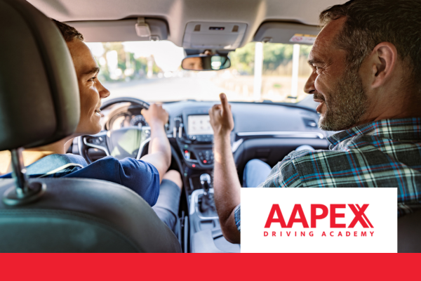 Young male driving car while male driving instructor sits in passenger seats and gives him the thumbs up, both are smiling 