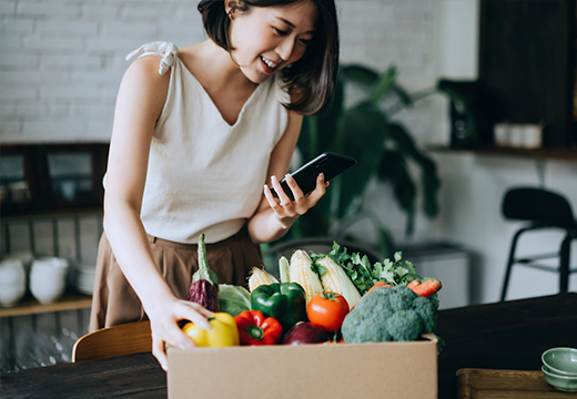 Young woman just received grocery order from her mobile device.