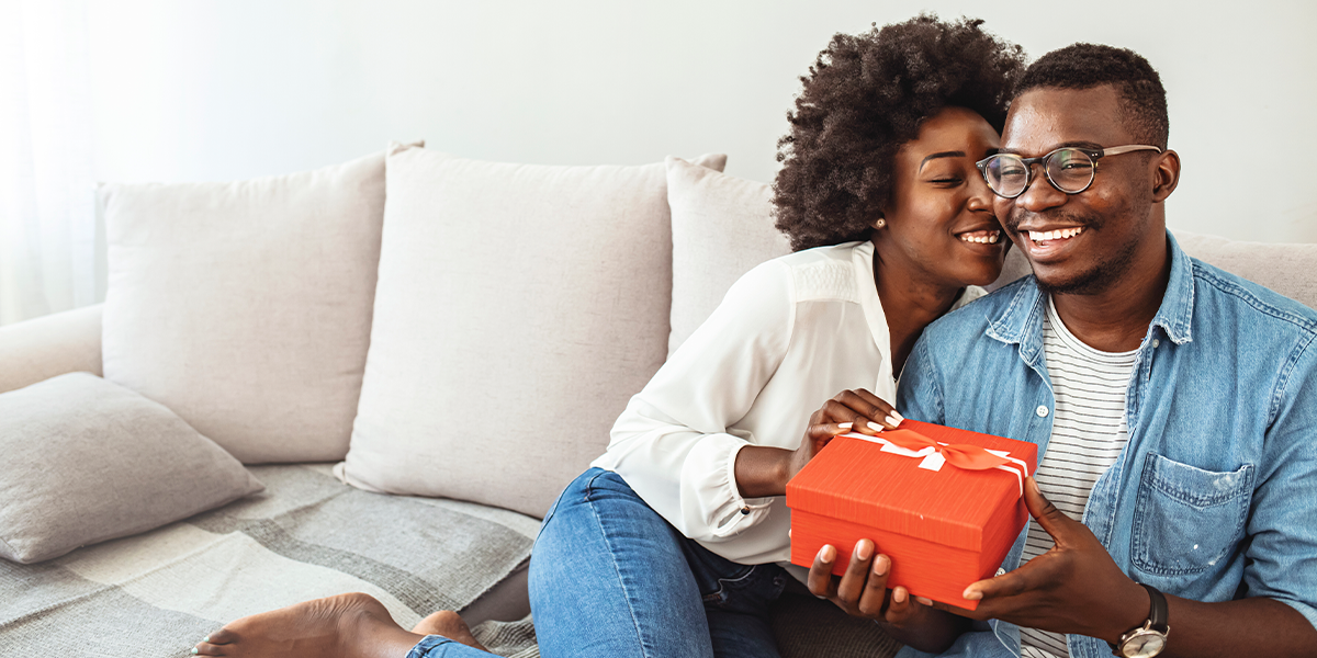 Young couple exchanging Valentine's Day gifts on couch