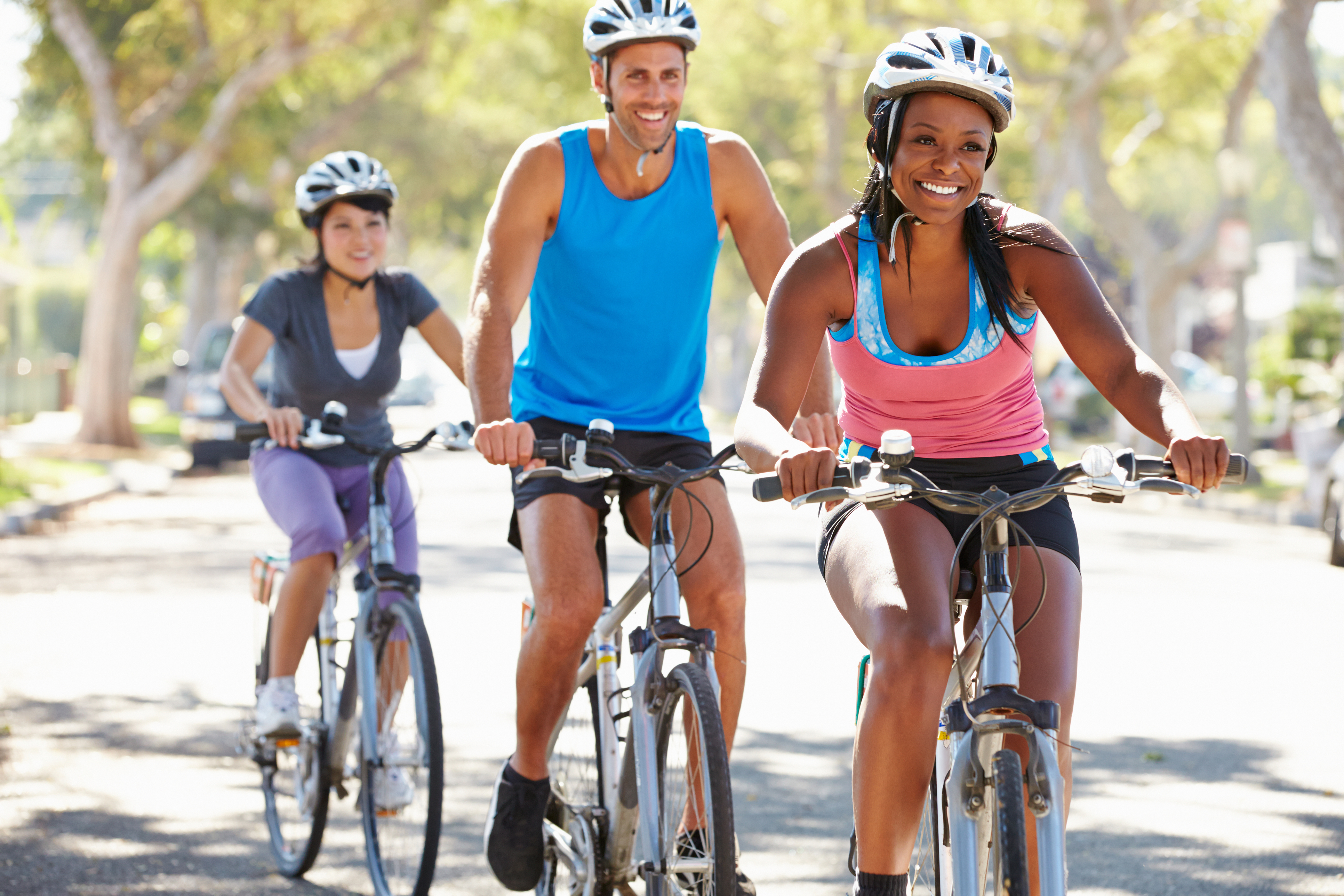 Three adults riding bicycles on a sunny day.